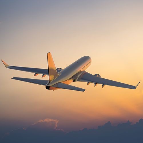A commercial airliner climbing at dusk.